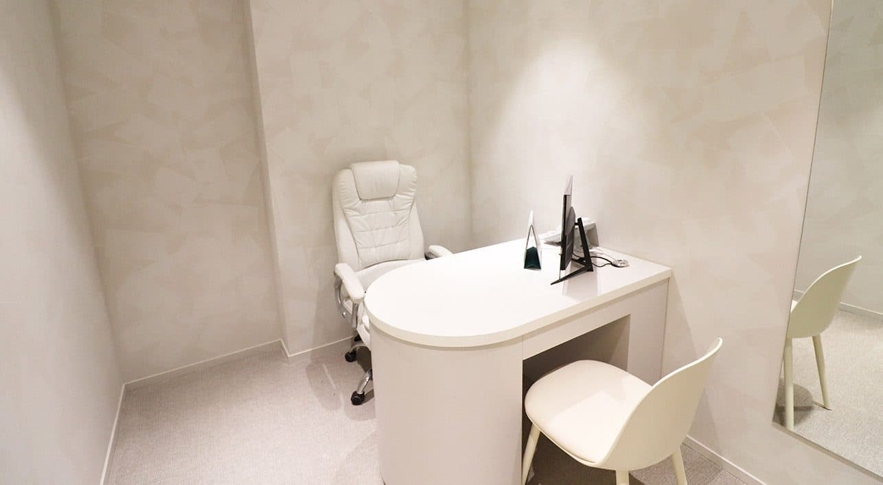 A private one-to-one consultation room with a desk, chairs and a full-length mirror