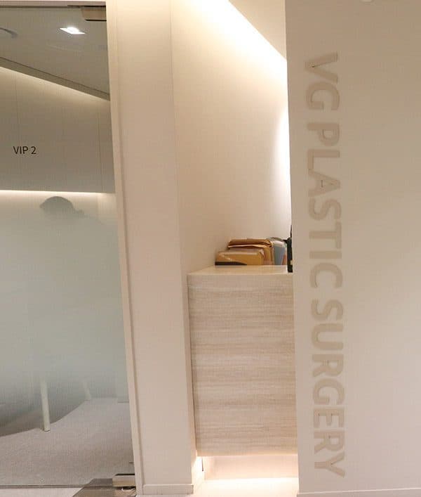 A pillar engraved VG PLASTIC SURGERY beside a private consultation room screened by frosted glass