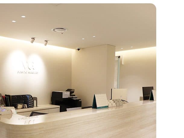 A reception desk with a stone counter and a lit brand mark on the wall